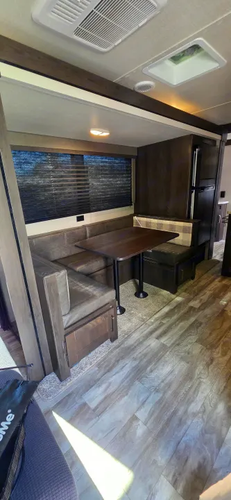 Spacious RV rental interior: comfortable U-shaped dinette, table, kitchen area, and wood-look flooring.. Grand Design Transcend Xplor 2021