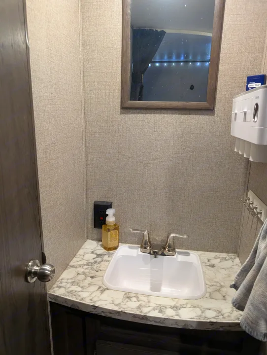 Inside an RV rental: a neat, compact bathroom vanity with a white sink, chrome faucet, marbled counter, and mirror.. Jayco Jay Flight 2020