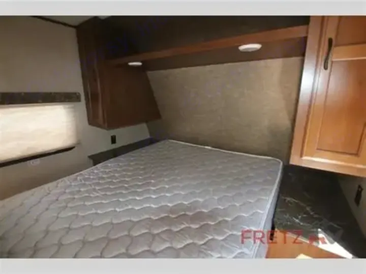 RV rental interior showing a cozy bedroom with a white mattress, overhead wood cabinets, and a window.. Jayco Jay Flight SLX 2016