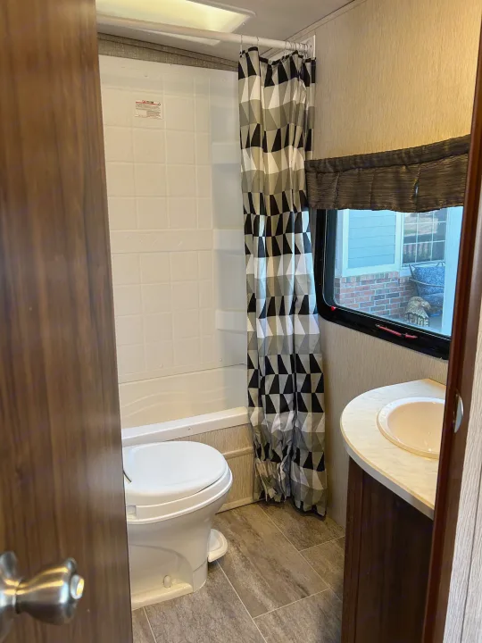 Inside an RV rental: a compact bathroom featuring a toilet, tiled shower, and vanity sink. Ideal for your travels.. Heartland RVs Mallard 2019