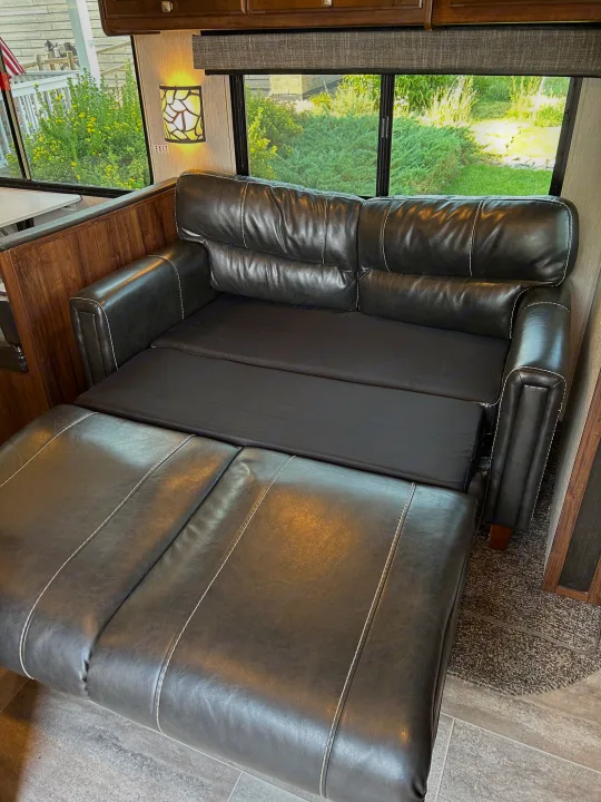 This RV rental's black leather sofa extends into a comfortable bed, offering flexible sleeping for your travels.. Heartland RVs Mallard 2019