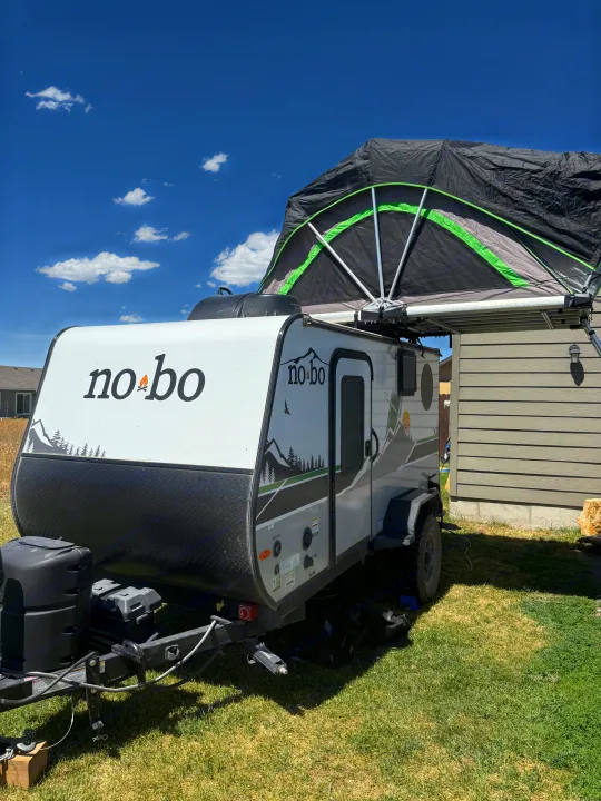 White no-bo travel trailer with an open rooftop tent, perfect for an RV rental. Sunny day, grassy yard.. Forest River Nobo 10.7 2024