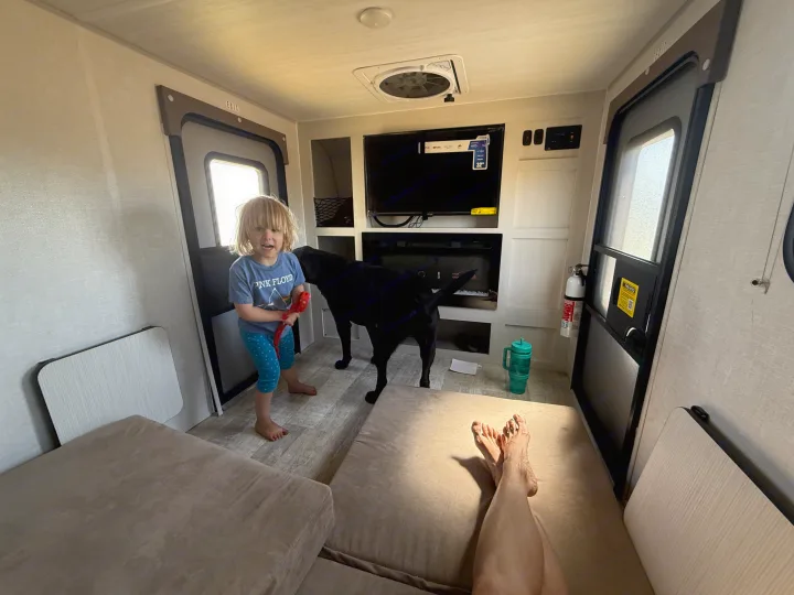 An RV rental's inviting interior with a child and their black dog. Perfect for cozy family travel.. Forest River Nobo 10.7 2024