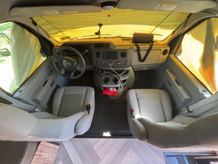 Bright interior of an RV rental Ford E-Series van, showing driver/passenger seats, dashboard, and full window sunshades.. 1FDWE3FNXSDD14715 Cross trail 22xgf 2025