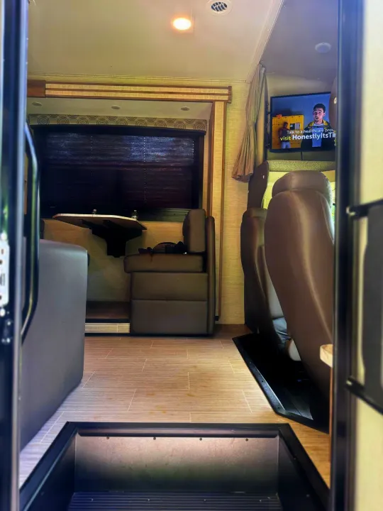 Step inside this RV rental! Modern interior with tan seating, dining table, window, and TV. Perfect for your next road trip.. Entegra Coach Odyssey 2021