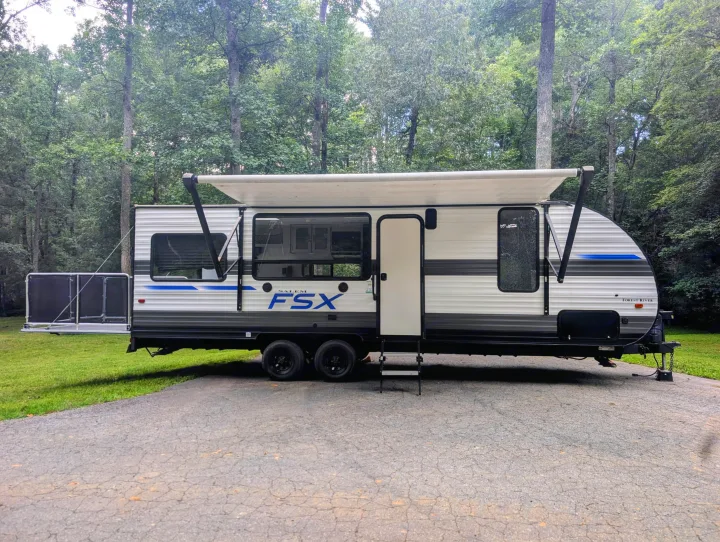 RV rental: Modern Forest River travel trailer with awning and rear patio, parked on asphalt with a forest backdrop.. Forest River Salem 2021