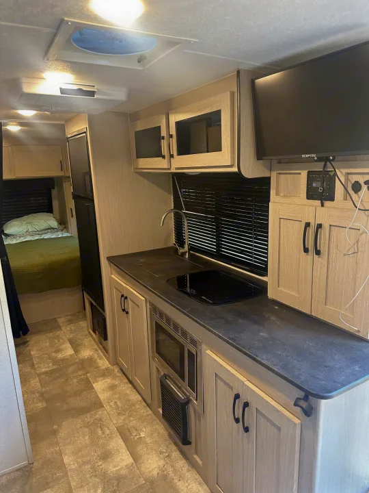 Modern rv rental interior with kitchen, TV, and bedroom. Enjoy a fully equipped space for your travel.. Coachmen Apex Nano - Off Grid 2022