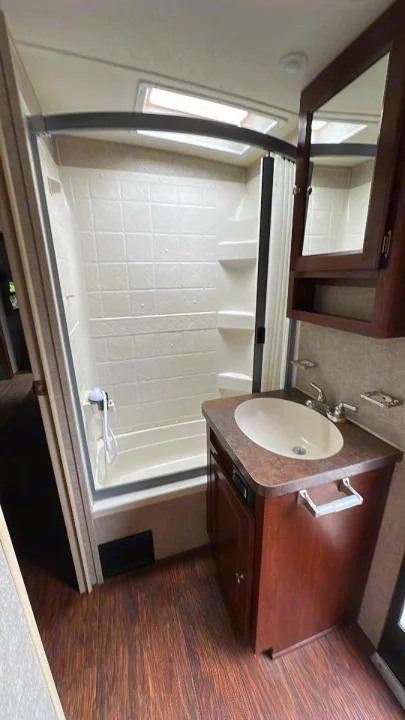 RV rental bathroom: bright shower with skylight, vanity with sink, mirrored cabinet, and wood-look floor.. Forest River Rockwood Signature Ultra Lite 2015