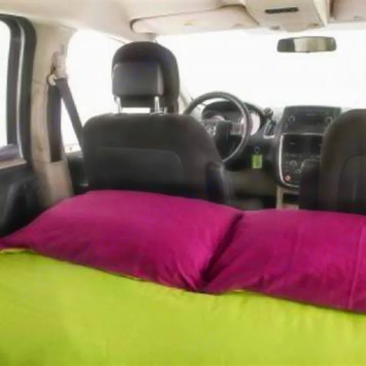 Minivan interior shows a green bed with pink pillows, ideal for car camping. A comfy RV rental alternative for road trips.. Dodge Caravan 2013