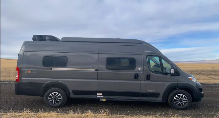 Sleek gray Winnebago Solis campervan, perfect for an rv rental road trip, parked in a vast, dry landscape.. Winnebago Solis 2025