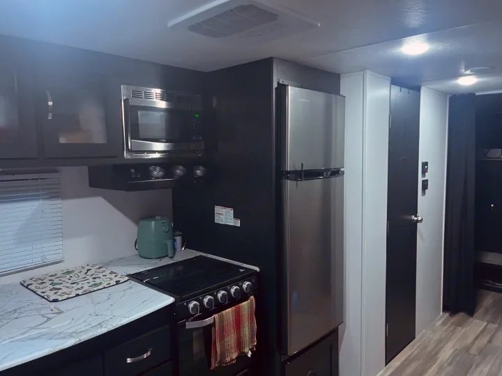 This modern RV rental kitchen has a microwave, gas stove, and refrigerator for convenient cooking on the road.. Coachmen 29SE 2022