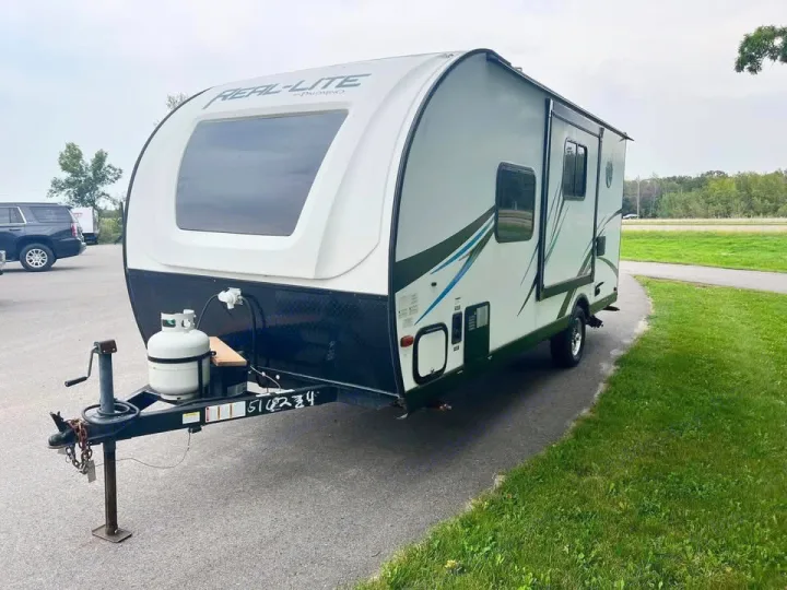 Palomino REAL-LITE travel trailer for RV rental. White & black, with large front window and side graphics.. Palomino Real Lite 2019