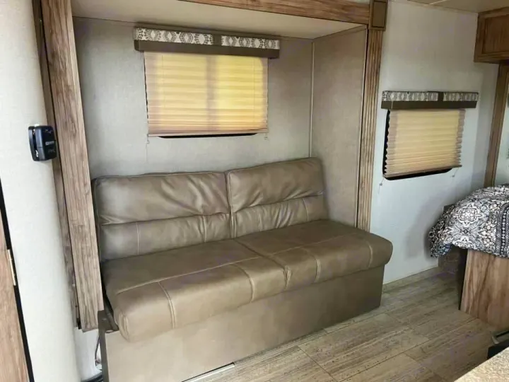 Inside an rv rental: a cozy living space with a light sofa, windows with shades, and part of a bed, ideal for travel.. Palomino Real Lite 2019