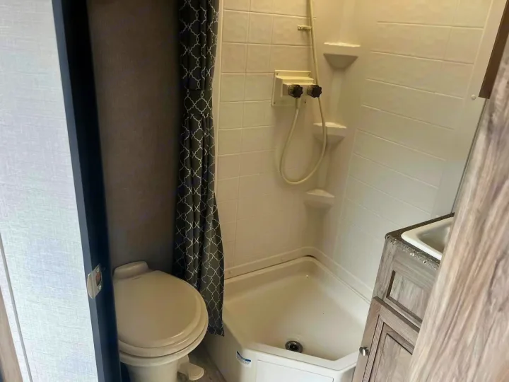 Compact RV rental bathroom with toilet, tiled shower stall, and vanity sink.. Palomino Real Lite 2019