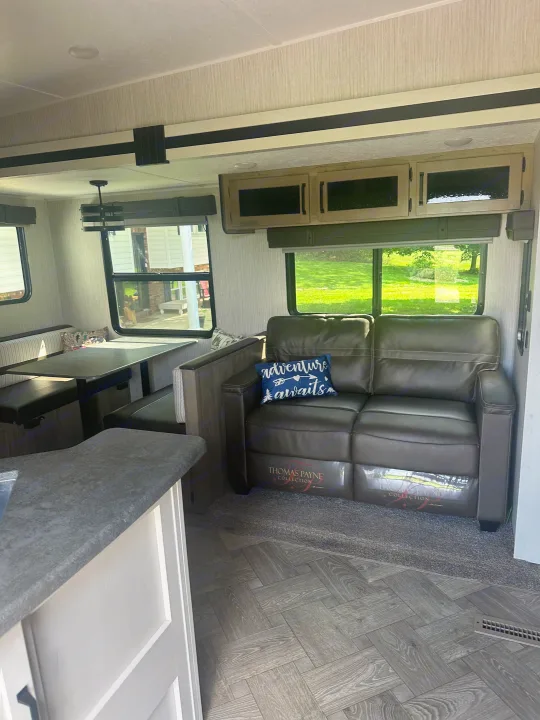 View inside an RV rental showing a comfortable living space with a dinette, sofa, and storage cabinetry.. Forest River Palomino Puma 2022