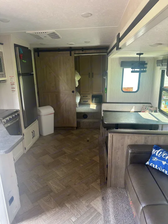Modern RV rental interior: kitchen, living space with dinette & sofa, plus a separate bunk/bedroom area.. Forest River Palomino Puma 2022