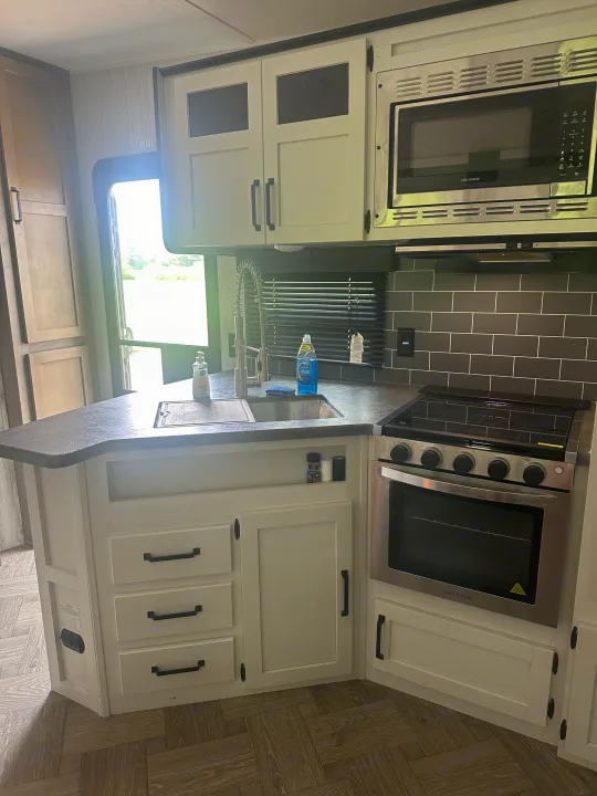 Modern RV rental living space with a large TV, electric fireplace, and functional storage cabinets. Light wood interior.. Forest River Palomino Puma 2022