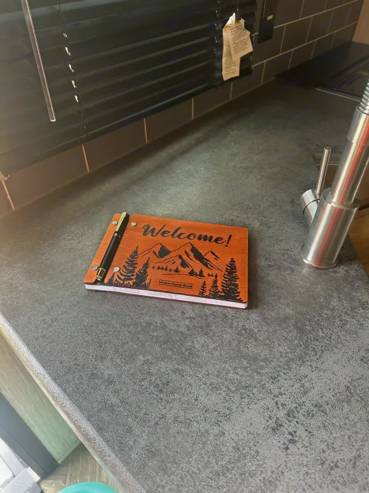 A "Welcome! Visitor Guest Book" on a gray countertop with a pen, inviting notes from your RV rental adventures.. Forest River Palomino Puma 2022