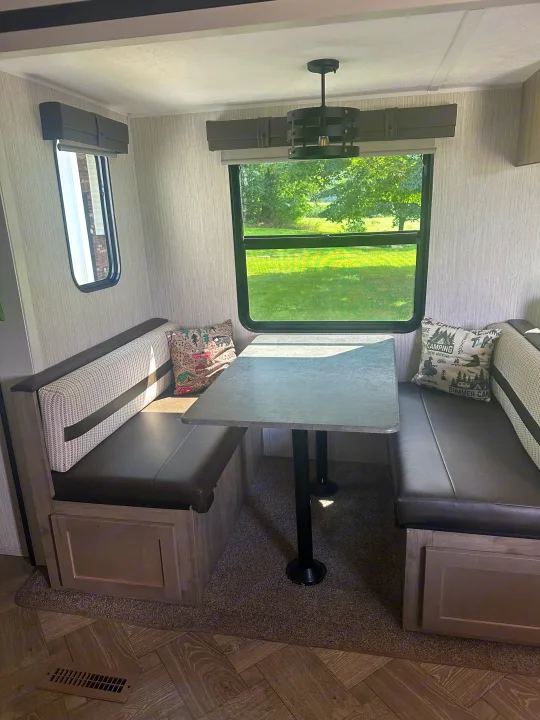 Enjoy this RV rental's cozy dinette with a table, padded booth seating, camping pillows, and bright windows.. Forest River Palomino Puma 2022