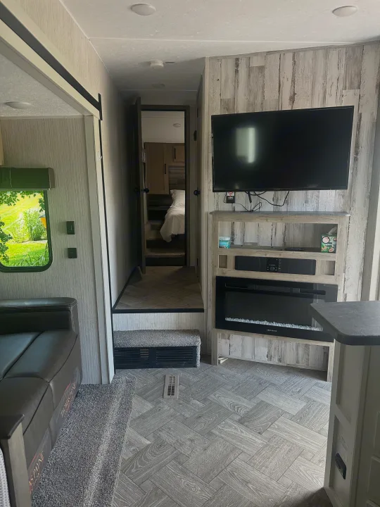 Inside an RV rental: a modern living space with TV, electric fireplace, and steps to the bedroom, showcasing stylish flooring.. Forest River Palomino Puma 2022