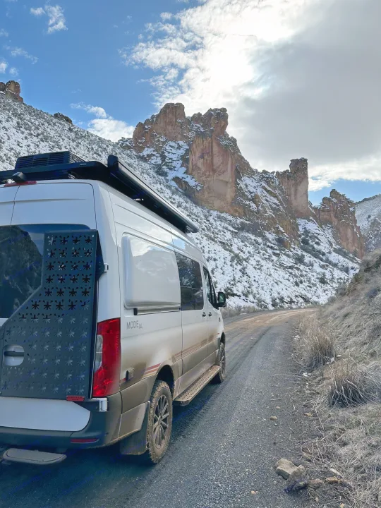 A rugged rv rental van on a snowy mountain dirt road, offering epic off-road adventure travel and scenic views.. Storyteller Overland Storyteller Overland Class B 2021
