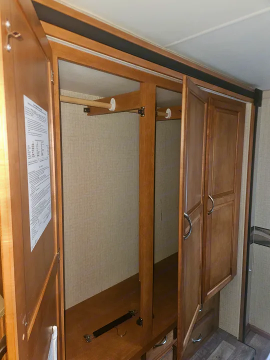 Inside an RV rental: a wooden wardrobe with hanging rod, lower storage area, and paneled doors, ideal for travel organization.. Other Other 2017