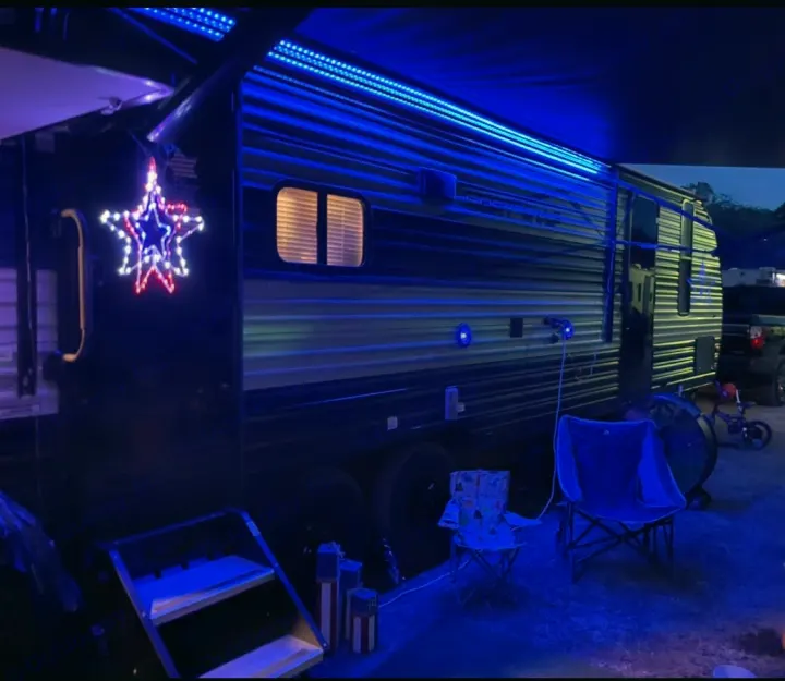 Illuminated RV rental at night: blue LED awning lights, patriotic star, and outdoor seating.. Forest River Cherokee Grey Wolf 2022