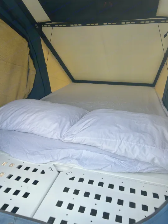 Cozy RV rental interior showing a neat bed with white pillows and sheets inside a pop-up tent with a perforated base.. Dodge Dodge 1 Ton Pu 2018