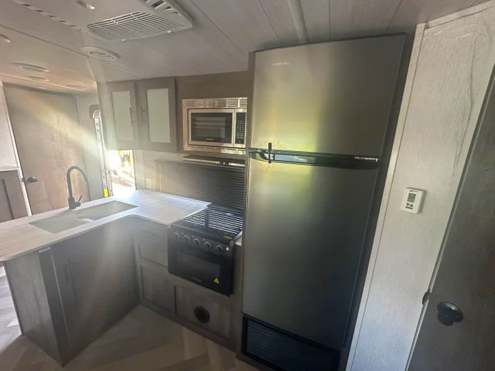 Modern RV rental kitchen with stainless Everchill fridge, Greystone microwave, stove, and sink. Bright interior for your adventures.. Forest River Salem Cruise Lite 2022