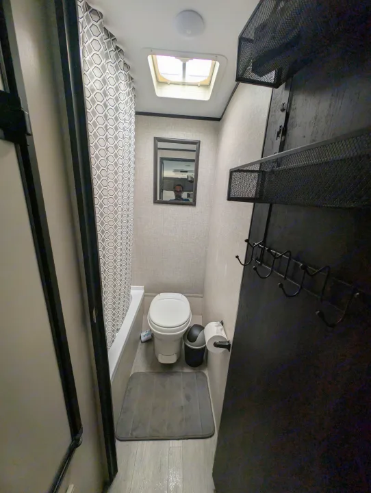 Compact RV rental bathroom, featuring a toilet, bathtub with shower, mirror, and skylight. Includes smart storage.. Jayco Jay Flight SLX 2022