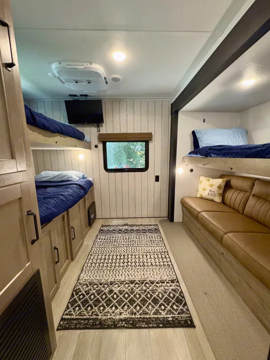 RV rental interior with cozy bunk beds, a comfy sofa, window view, and air conditioning for your adventures.. Forest River Puma 2026