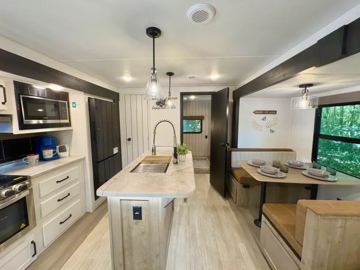 Modern RV rental kitchen and dining area featuring an island with sink, full appliances, and a cozy booth set for meals.. Forest River Puma 2026