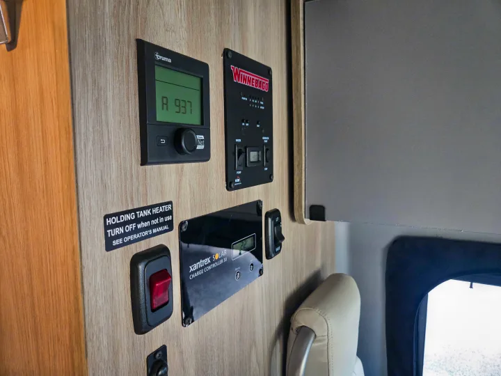 This RV rental interior shows control panels: Truma heater, Winnebago system, Xantrex solar, and holding tank heater switch.. Winnebago Solis 2021