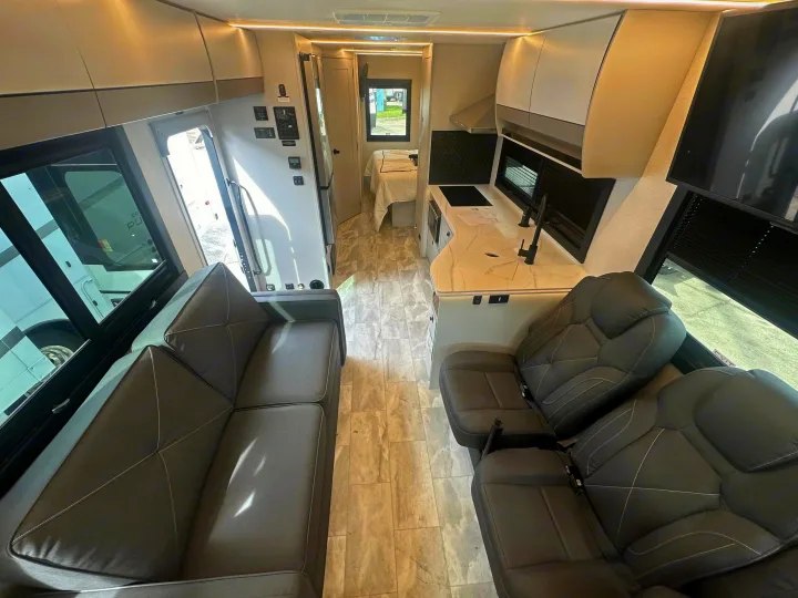 Inside an RV rental: a modern interior with a sofa, full kitchen, front seats, and a glimpse of the bedroom beyond.. Coachmen Euro 2025