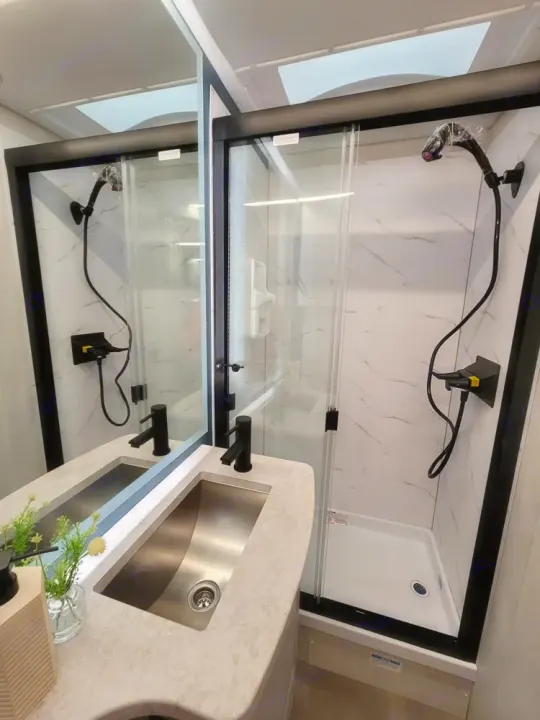 Step into this modern RV rental bathroom featuring a stainless steel sink, black faucet, and chic marbled shower.. Coachmen Euro 2025