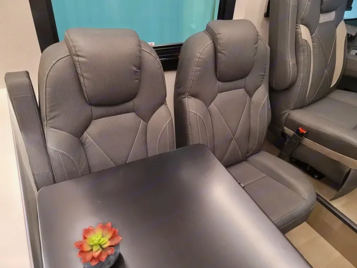 Comfortable gray seats and a black table are central in this RV rental interior, ready for your journey.. Coachmen Euro 2025