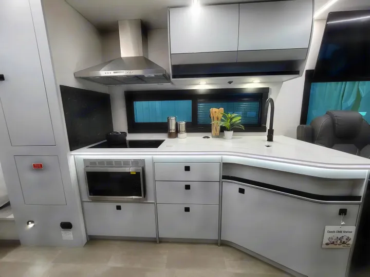 Modern RV rental kitchen with induction cooktop, microwave, and sink in a compact, sleek design.. Coachmen Euro 2025