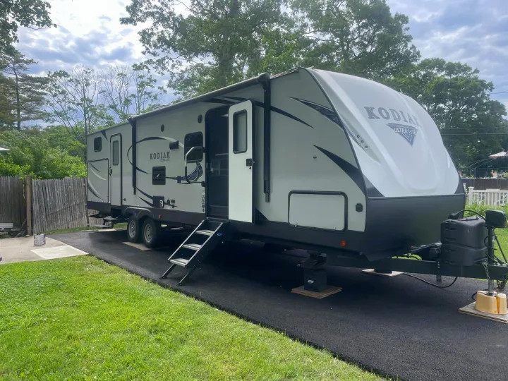 Grey Kodiak Ultra Lite RV rental, parked on paved driveway with steps down. Ready for your next adventure!. Dutchmen Kodiak Ultra-Light 2018