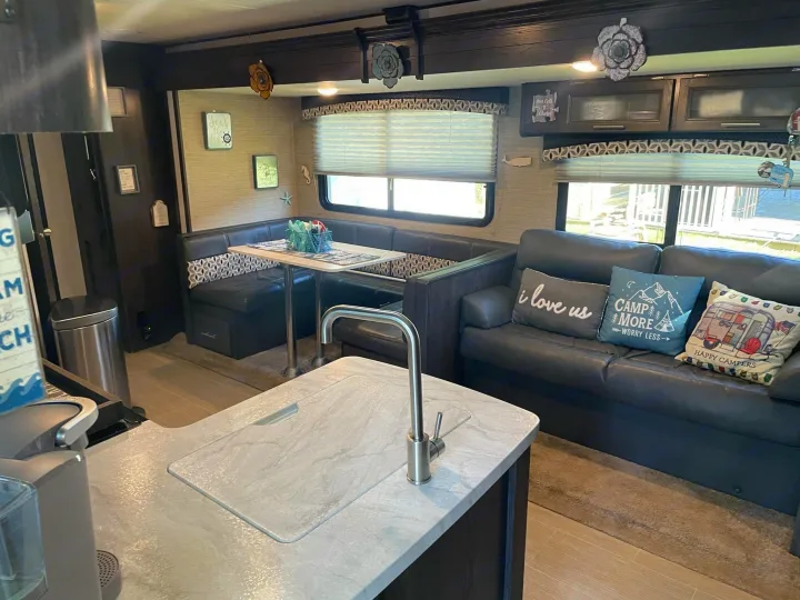 Explore this RV rental's comfortable interior: kitchenette, U-shaped dinette, and dark sofa.. Dutchmen Kodiak Ultra-Light 2018