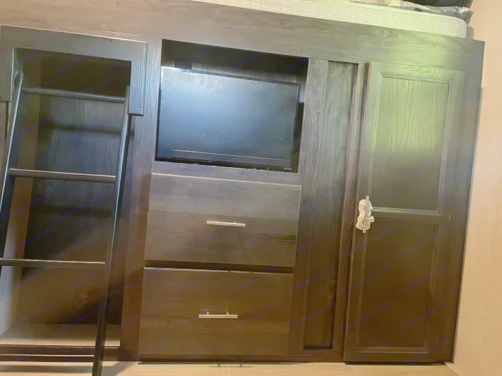 Dark wood RV rental interior featuring a bunk bed with ladder, integrated TV, drawers, and wardrobe for efficient storage.. Dutchmen Kodiak Ultra-Light 2018
