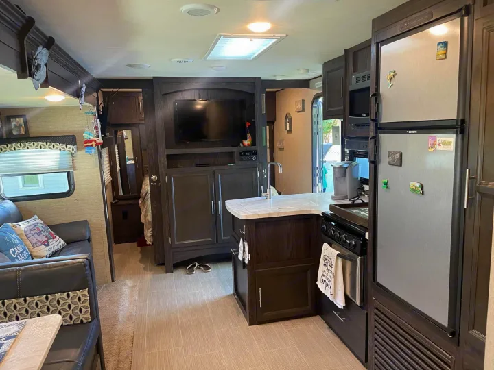 Modern RV rental interior with kitchen island, fridge, stove, and living area with TV and couch.. Dutchmen Kodiak Ultra-Light 2018