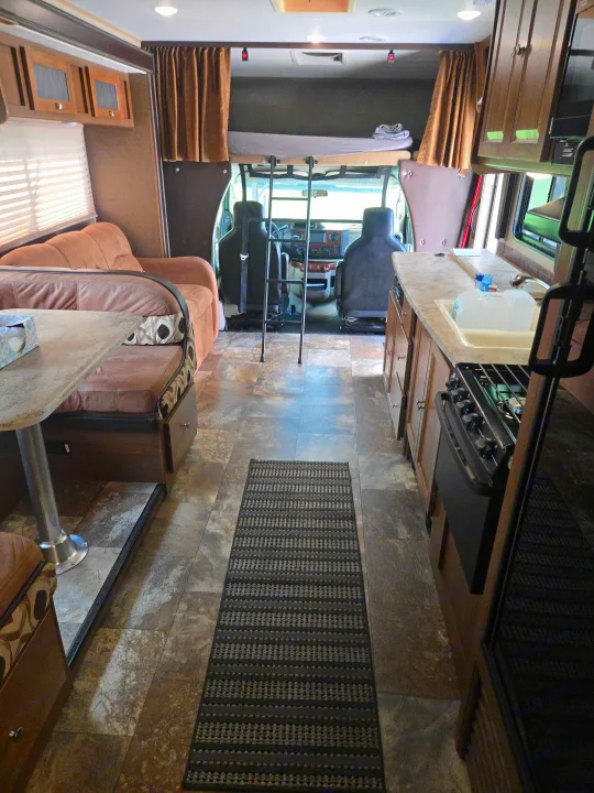 Spacious RV rental interior featuring a living area, dinette, full kitchen, and overhead bunk above the cockpit. Perfect for travel!. Forest River Coachmen Leprechaun 2017