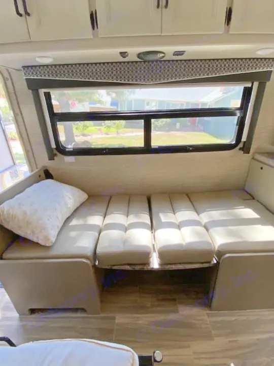 RV rental: Convertible dinette/bed with light cushions, large window showing outdoor view.. Thor Axis 2023