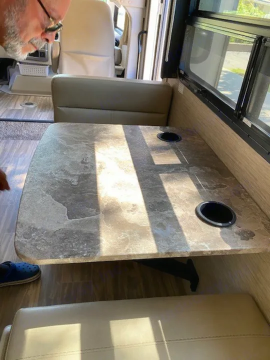 RV rental interior: A well-lit dinette area featuring a textured table with two cup holders and comfortable bench seating.. Thor Axis 2023