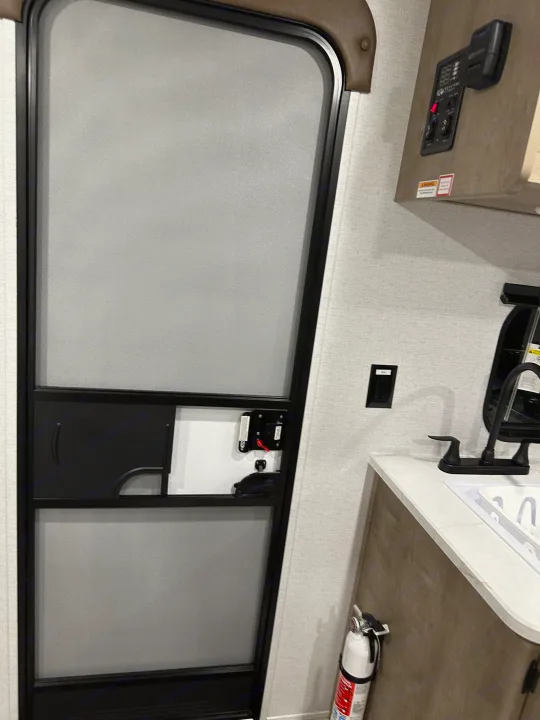 Experience comfort in this RV rental: interior features screen door, control panel, kitchen sink, and fire extinguisher.. Keystone RV Springdale Mini 2025
