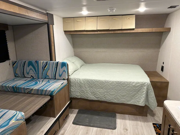 Modern RV rental interior with a comfy bed, versatile dinette seating, and practical overhead storage.. Keystone RV Springdale Mini 2025