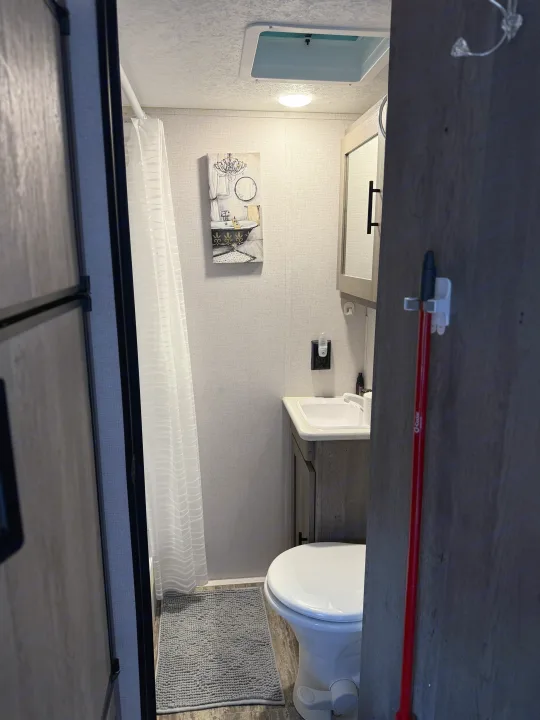RV rental: A look inside a functional bathroom with a shower, toilet, vanity, and charming decor for your travels.. Keystone RV Springdale 2022