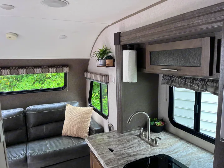 This RV rental interior showcases a comfortable sofa, compact kitchen with sink, and large windows with scenic views.. R-Pod R-Pod Trailer 2018