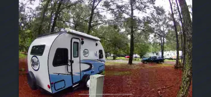 Experience nature with an RV rental! A compact R-Pod travel trailer is parked at a wooded campsite, ready for your next adventure.. R-Pod R-Pod Trailer 2018