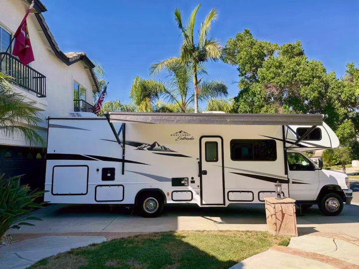 Spacious white motorhome (RV rental) parked in a sunny suburban driveway, ready for new journeys and adventures.. Forest River ENTRADA 3100FB 2024